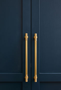 close up of blue cabinet doors with long gold handles